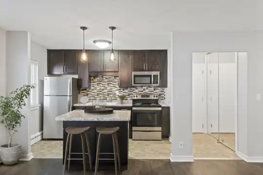 kitchen with stainless steel appliances, electric range oven, granite-like countertops, pendant lighting, light parquet floors, and dark brown cabinets