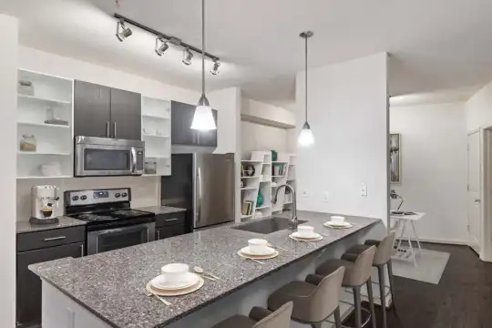kitchen featuring a breakfast bar, stainless steel appliances, electric range oven, pendant lighting, light stone countertops, dark brown cabinetry, and dark hardwood flooring