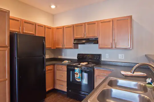 kitchen with refrigerator, electric range oven, extractor fan, dark countertops, brown cabinets, and dark hardwood flooring