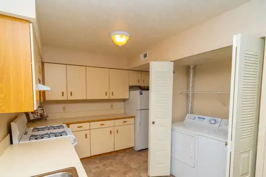 clothes washing area with tile floors, gas cooktop, refrigerator, and separate washer and dryer