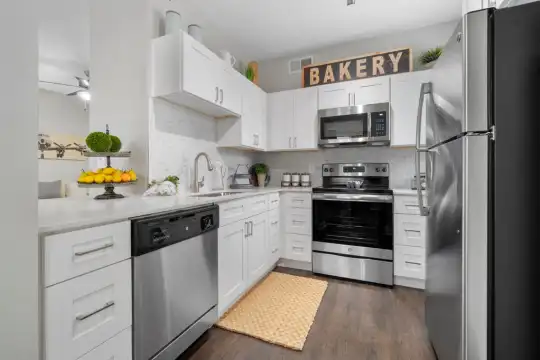 kitchen with stainless steel appliances, range oven, white cabinets, dark parquet floors, and light countertops