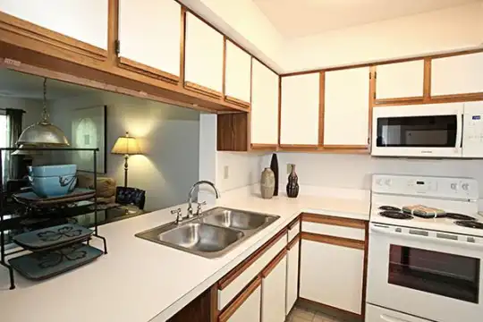 kitchen with stainless steel microwave, electric range oven, white cabinetry, light flooring, light countertops, and pendant lighting