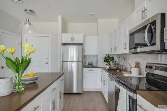 kitchen with electric range oven, stainless steel appliances, white cabinets, pendant lighting, and light parquet floors