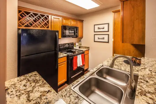 kitchen with refrigerator, electric range oven, microwave, brown cabinets, and dark stone countertops