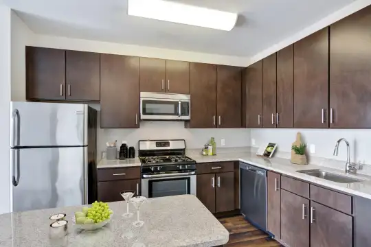 kitchen featuring gas range oven, stainless steel appliances, dark brown cabinetry, dark flooring, and light countertops