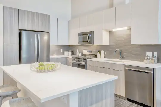 kitchen featuring stainless steel appliances, gas range oven, white cabinetry, light parquet floors, and light countertops