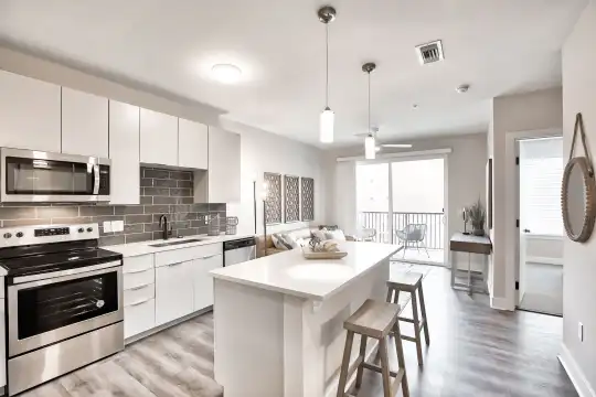 kitchen featuring a wealth of natural light, a kitchen breakfast bar, stainless steel microwave, electric range oven, dishwasher, white cabinets, pendant lighting, light countertops, and light hardwood floors