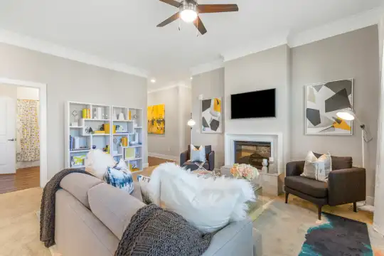 hardwood floored living room featuring a ceiling fan, a fireplace, and TV