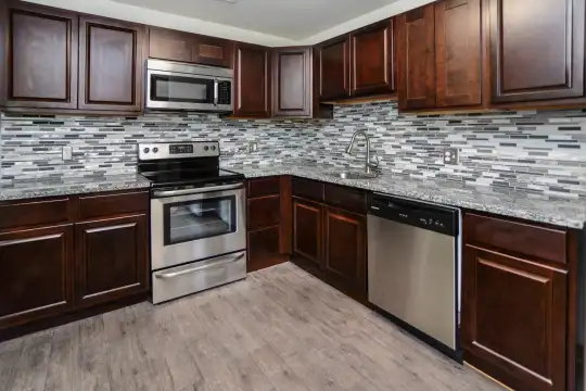 kitchen featuring stainless steel appliances, electric range oven, dark brown cabinetry, light granite-like countertops, and light parquet floors