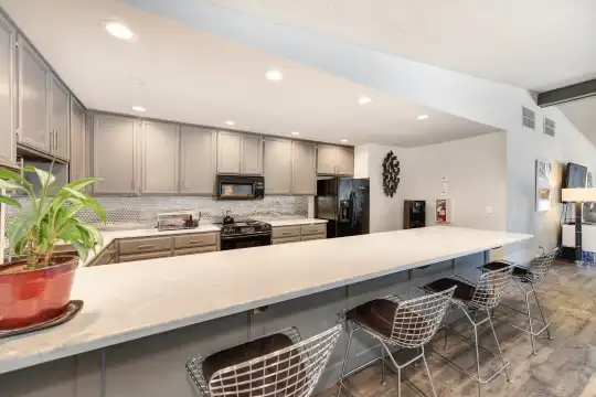 kitchen featuring a breakfast bar area, refrigerator, microwave, range oven, dark flooring, white cabinets, and light countertops