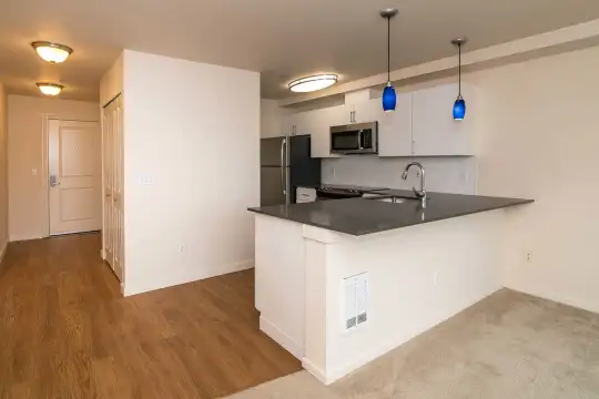 kitchen featuring refrigerator, microwave, pendant lighting, dark countertops, white cabinetry, and light hardwood flooring