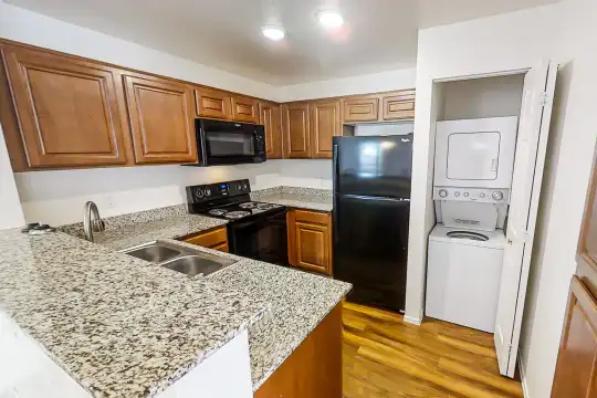 kitchen featuring washer / dryer, refrigerator, electric range oven, microwave, dark parquet floors, light stone countertops, and brown cabinets