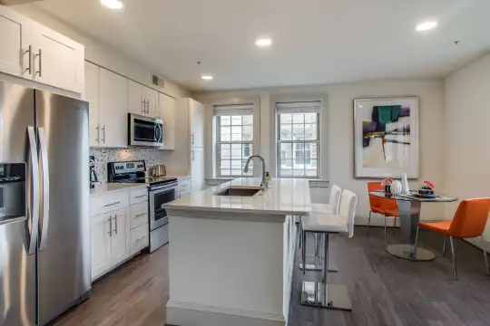 kitchen with a healthy amount of sunlight, a center island, a breakfast bar, stainless steel appliances, electric range oven, dark hardwood flooring, white cabinetry, and light countertops