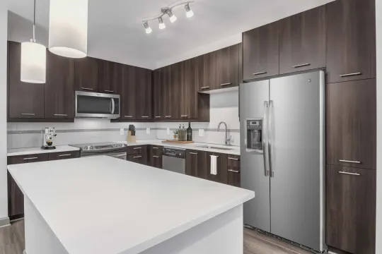 kitchen featuring a center island, stainless steel appliances, range oven, pendant lighting, light countertops, dark brown cabinets, and light parquet floors