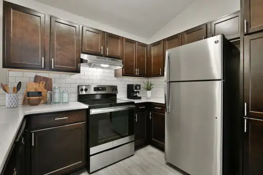 kitchen featuring stainless steel refrigerator, electric range oven, fume extractor, light stone countertops, light parquet floors, and dark brown cabinets