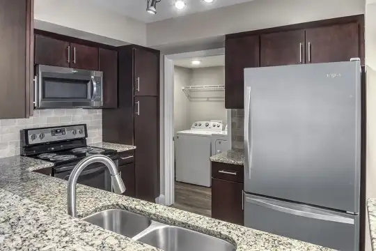 kitchen featuring washer / dryer, electric range oven, stainless steel appliances, granite-like countertops, light hardwood floors, and dark brown cabinets