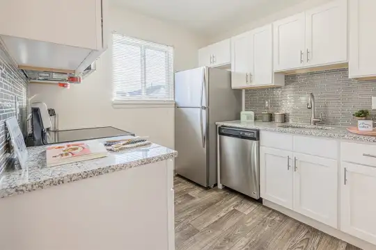 kitchen with natural light, stainless steel appliances, white cabinets, light stone countertops, and light parquet floors