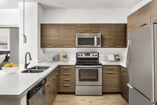 kitchen featuring electric range oven, stainless steel appliances, dark brown cabinetry, light hardwood floors, light countertops, and pendant lighting