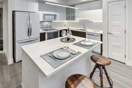 kitchen with a kitchen breakfast bar, stainless steel refrigerator, dishwasher, electric range oven, microwave, white cabinetry, light hardwood floors, and light countertops