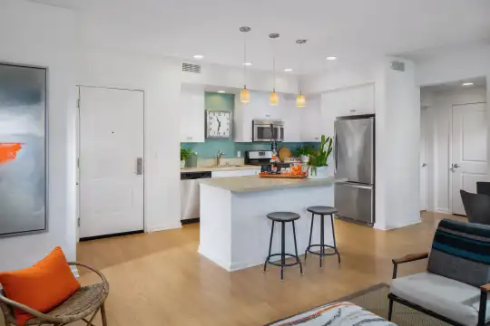 kitchen with a kitchen breakfast bar, range oven, stainless steel refrigerator, dishwasher, microwave, pendant lighting, light countertops, white cabinetry, and light parquet floors