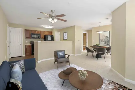 carpeted living room with a ceiling fan, refrigerator, and microwave