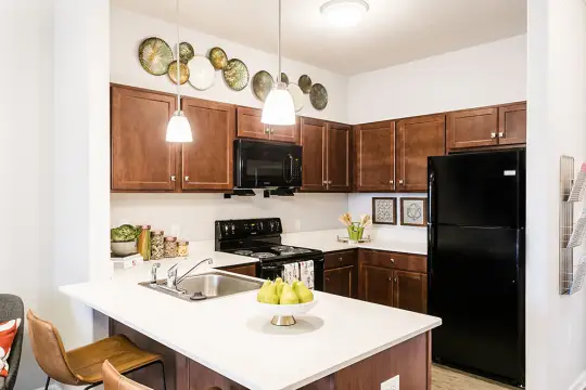 kitchen featuring a breakfast bar area, refrigerator, electric range oven, microwave, light countertops, pendant lighting, dark brown cabinets, and light flooring