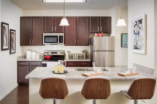 kitchen with stainless steel appliances, electric range oven, dark hardwood flooring, pendant lighting, dark brown cabinetry, and light countertops