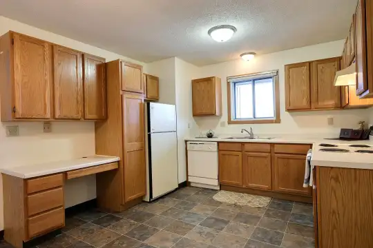 kitchen with natural light, refrigerator, dishwasher, electric range oven, fume extractor, dark tile floors, brown cabinets, and light countertops