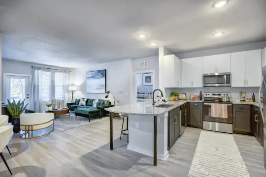kitchen with a breakfast bar, natural light, stainless steel microwave, electric range oven, dishwasher, white cabinetry, light granite-like countertops, and light hardwood floors