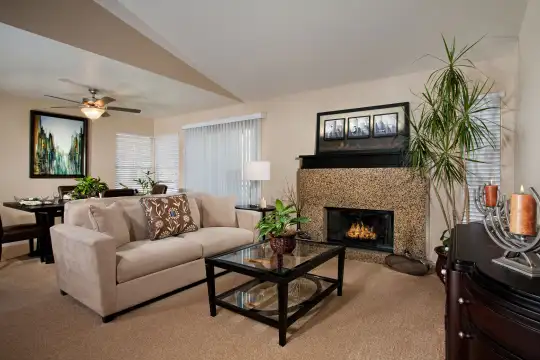 carpeted living room with vaulted ceiling, a ceiling fan, and a fireplace