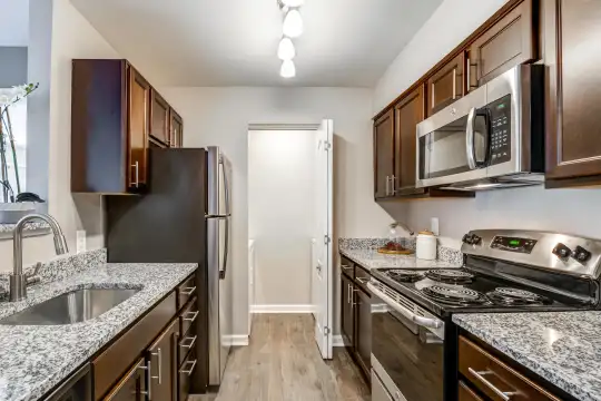 kitchen with refrigerator, electric range oven, stainless steel microwave, light parquet floors, light granite-like countertops, and dark brown cabinets