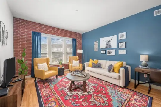 living room with hardwood floors, exposed bricks, and TV