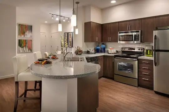 kitchen with a kitchen breakfast bar, a kitchen island, electric range oven, stainless steel appliances, dark brown cabinetry, light hardwood floors, light granite-like countertops, and pendant lighting