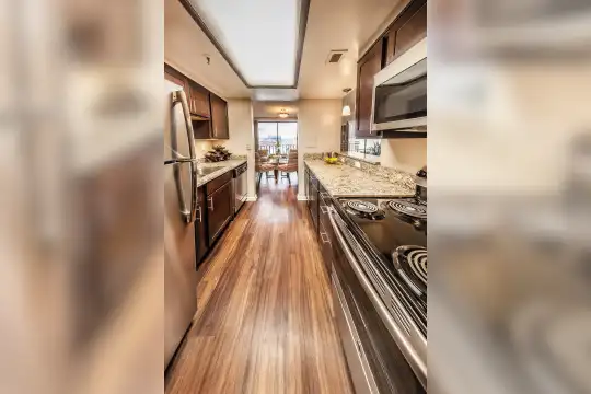 kitchen featuring parquet floors, electric cooktop, stainless steel refrigerator, dishwasher, microwave, pendant lighting, light granite-like countertops, and dark brown cabinets