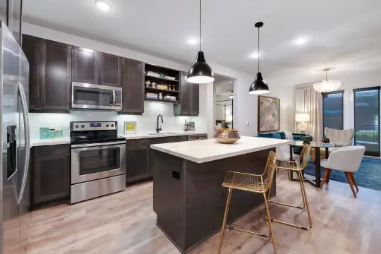 kitchen with a kitchen breakfast bar, a kitchen island, electric range oven, stainless steel appliances, dark brown cabinetry, light countertops, light hardwood floors, and pendant lighting