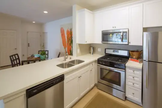 kitchen with stainless steel appliances, gas range oven, white cabinetry, light hardwood flooring, and light countertops