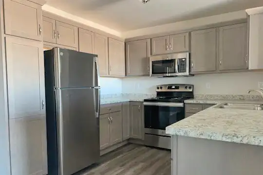 kitchen with stainless steel appliances, electric range oven, granite-like countertops, light brown cabinets, and light hardwood floors