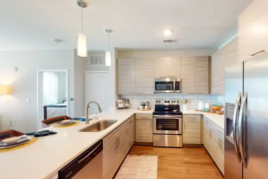 kitchen featuring electric range oven, stainless steel appliances, light brown cabinetry, light countertops, pendant lighting, and light parquet floors