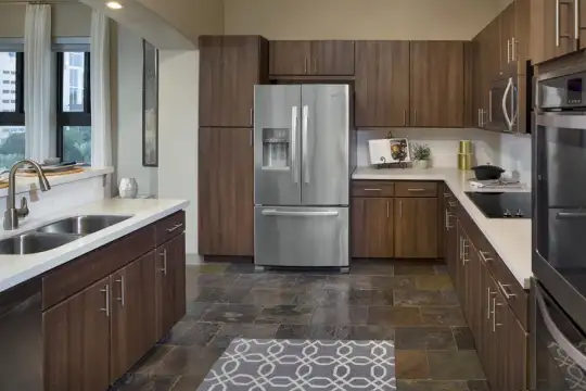 kitchen featuring electric cooktop, stainless steel appliances including a double oven, dark brown cabinets, light countertops, and dark tile flooring