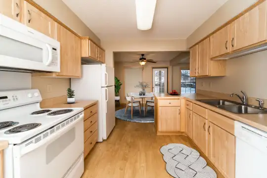 kitchen featuring natural light, refrigerator, dishwasher, electric range oven, microwave, light hardwood flooring, light brown cabinetry, and light countertops