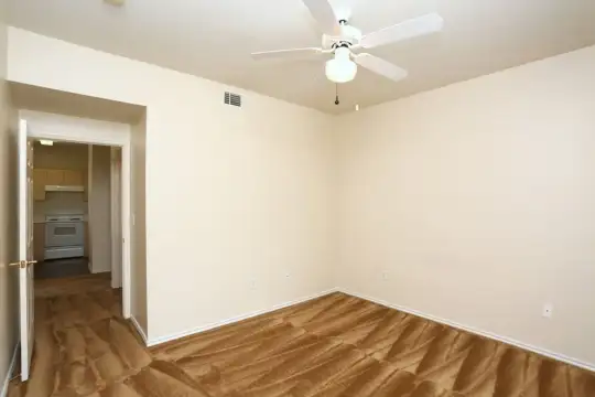 wood floored empty room featuring a ceiling fan, range oven, and exhaust hood