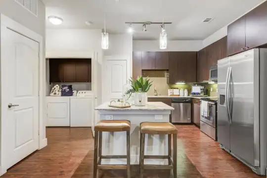 kitchen with stainless steel appliances, separate washer and dryer, range oven, granite-like countertops, dark hardwood floors, pendant lighting, and dark brown cabinetry