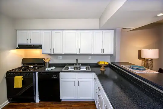 kitchen featuring exhaust hood, gas range oven, dishwasher, dark countertops, dark parquet floors, and white cabinetry