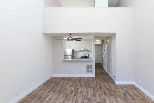 hardwood floored living room with a ceiling fan, refrigerator, range oven, and exhaust hood