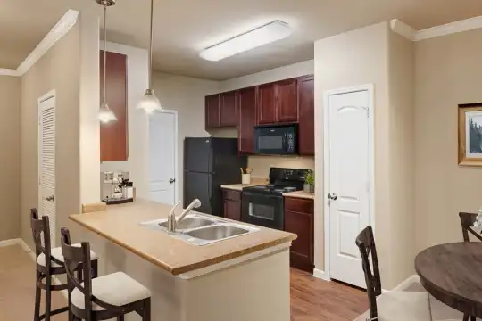 kitchen featuring a kitchen bar, refrigerator, electric range oven, microwave, light flooring, dark brown cabinetry, light countertops, and pendant lighting