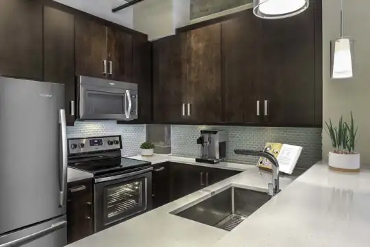 kitchen with electric range oven, stainless steel appliances, dark brown cabinetry, light countertops, and pendant lighting