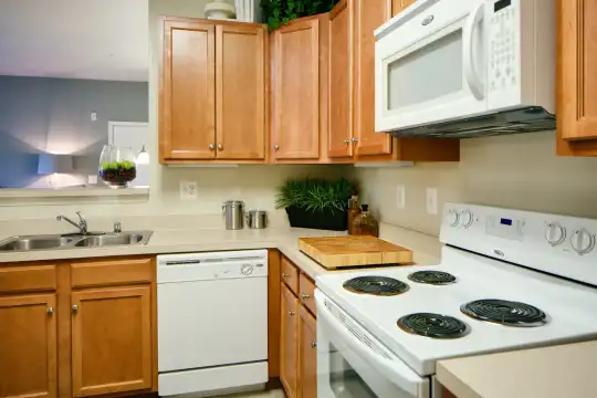 kitchen featuring electric range oven, dishwasher, microwave, brown cabinetry, and light countertops