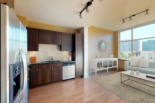 living room featuring a healthy amount of sunlight, hardwood flooring, stainless steel refrigerator, and dishwasher