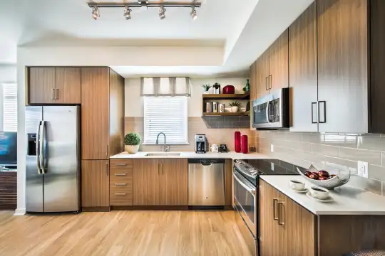 kitchen with natural light, electric range oven, stainless steel appliances, light countertops, dark brown cabinets, and light parquet floors