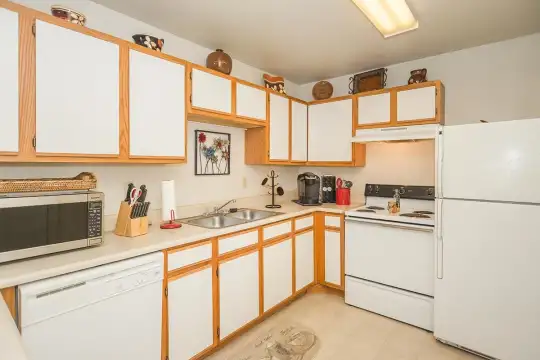 kitchen featuring refrigerator, microwave, fume extractor, electric range oven, dishwasher, light tile floors, light brown cabinets, and light countertops